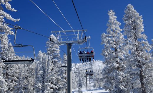 Snow covered chair lift, wintertime skiers, blue skies, Heavenly Mountain, Lake Tahoe, Nevada.